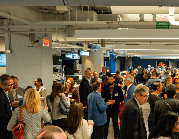 A large group of attendees mingle and network during the Shining Light Regional Cooperation Awards reception inside a modern event space.