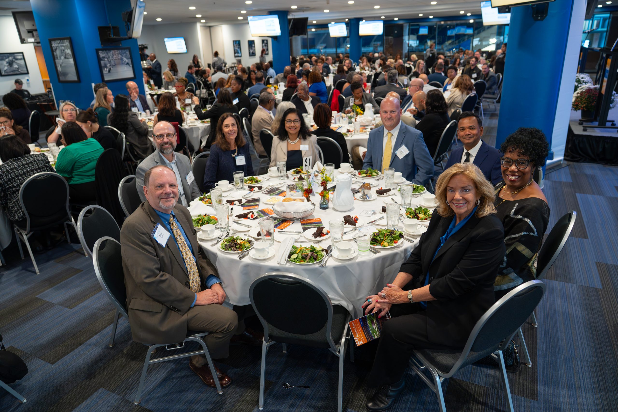 Elegant group of diverse professionals at the Shining Light Awards event, networking and celebrating achievements, showcasing a vibrant awards ceremony in a modern conference hall.