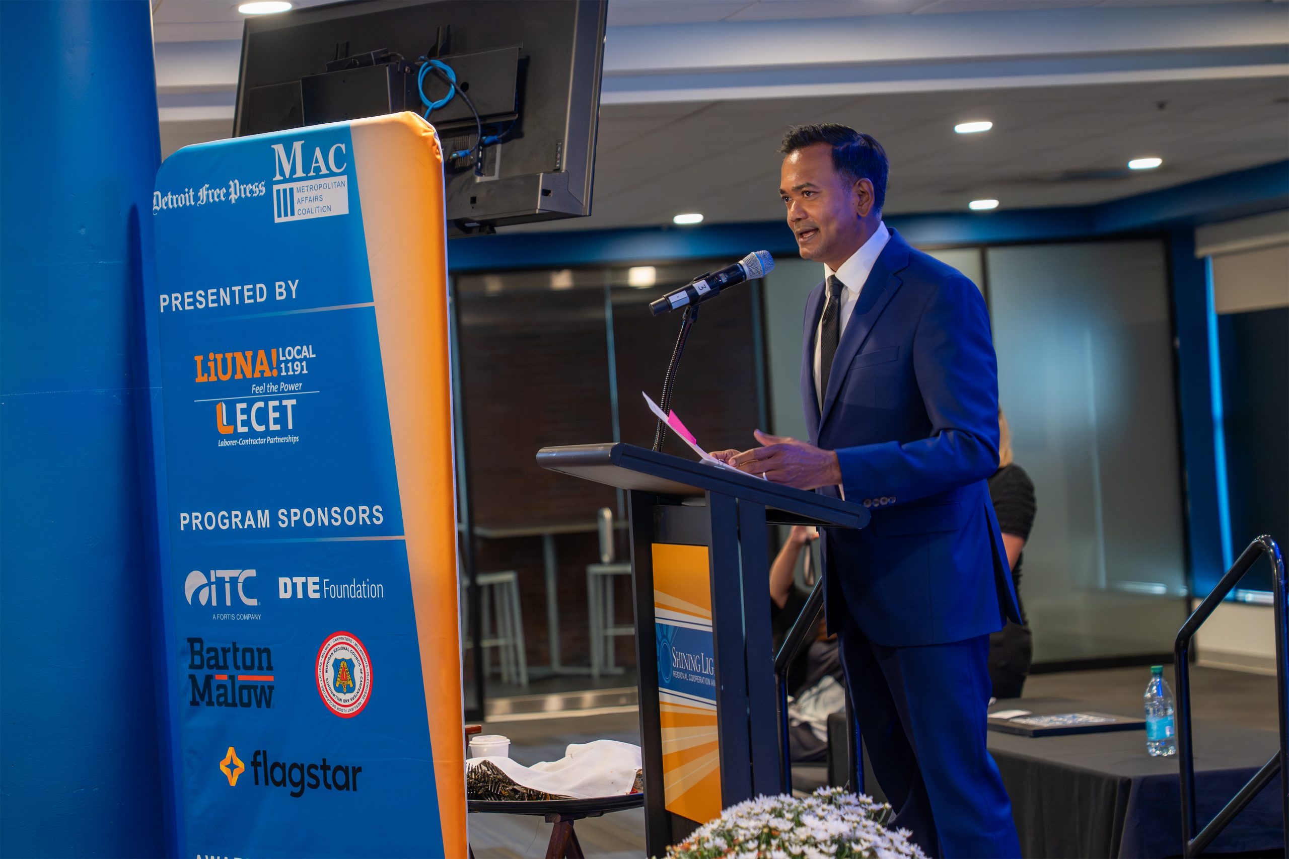 Inspiring professional speaker presenting at the Shining Light Awards event, emphasizing leadership and community impact in a formal indoor conference setting.