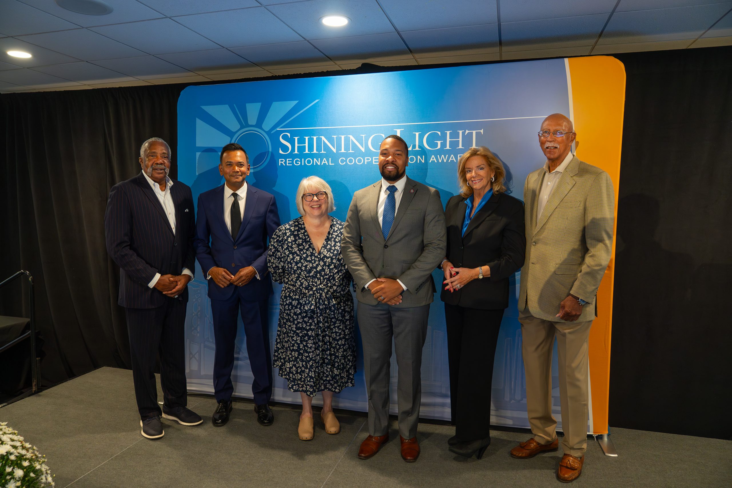 Shining Light Regional Cooperative Awards ceremony with diverse group of professionals posing on stage.
